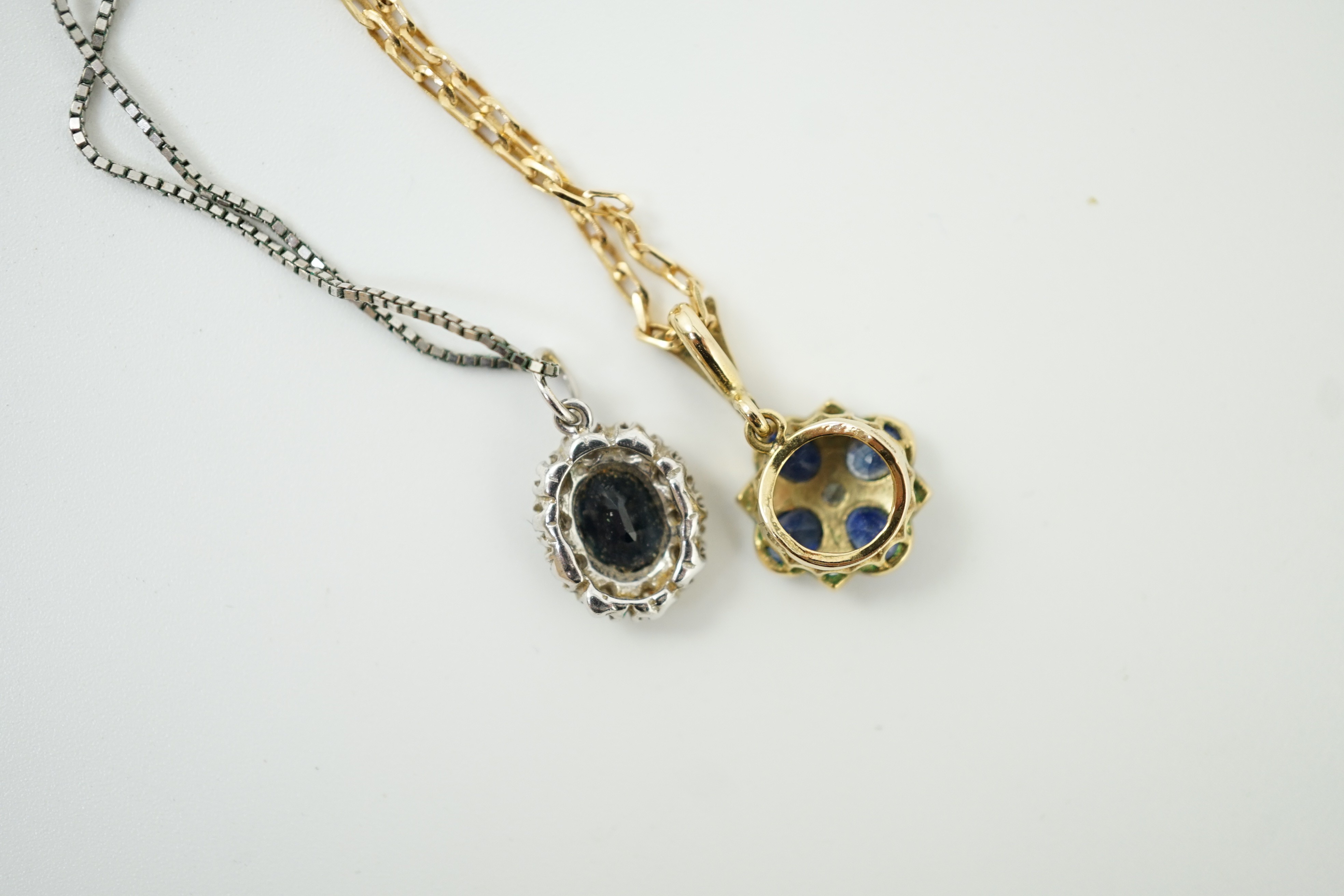 A modern 9ct gold, sapphire and diamond set pendant, overall 19mm, on a 375 chain, 38cm and a similar white metal, sapphire and diamond set pendant, on a 9ct white metal chain, gross weight 7 grams.